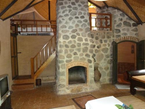 a living room with a stone fireplace and stairs at Little Eden Guesthouse in Pang Mapha