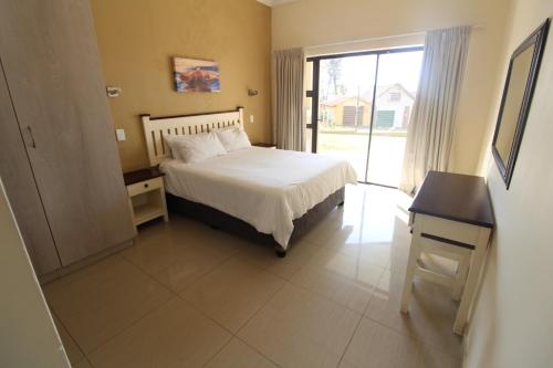 a bedroom with a bed and a desk and a window at Saints View Resort Unit 1 in Uvongo Beach