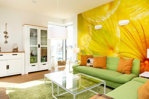 sala de estar con sofá verde y pared amarilla en Traumfängerloge -Hafenresidenz en Waren