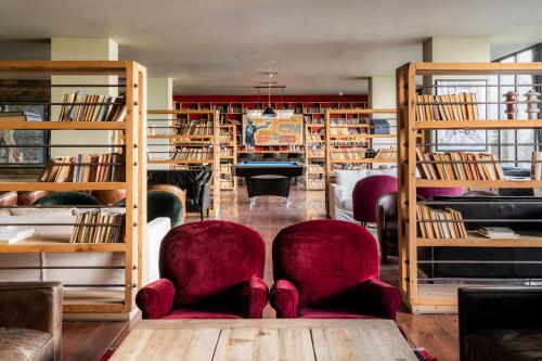 a library with two chairs and shelves of books at Rooms Hotel Kazbegi in Kazbegi