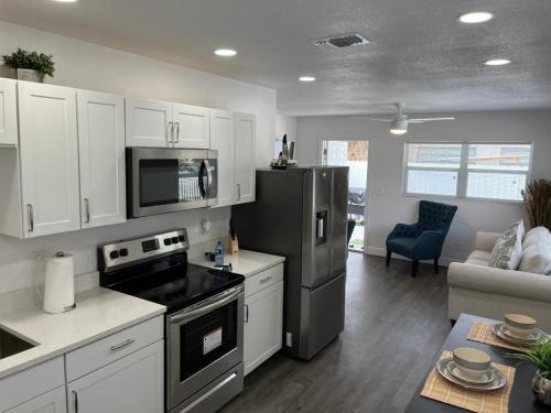 cocina con armarios blancos y nevera negra en Incredible comfortable apartments near the airport and beaches en Tampa