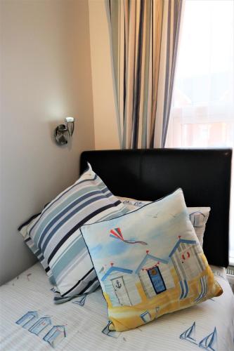 a bed with a pillow on it with a window at The Pebbles - Adults Only in Weymouth