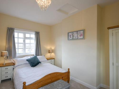 a bedroom with a bed and a window and a chandelier at The Retreat in Whitchurch