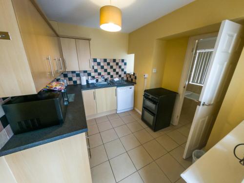 a small kitchen with a sink and a stove at NEWTON HEATH APARTMENT -750mtrs to beach - Spacious ground floor - Sleeps 6 in Porthcawl