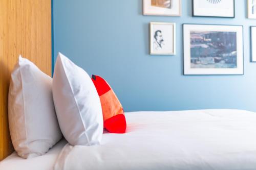 a bed with white pillows and pictures on the wall at Vie Via - Your Hotel in Leeuwarden