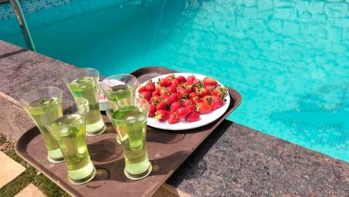 a plate of strawberries and drinks on a tray next to a pool at Riyansh Villa 5 bhk with Swimming Pool in Panchgani
