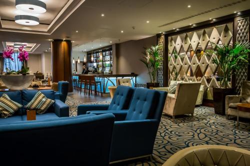 un vestíbulo con sofás azules y un restaurante en Holiday Inn London Kensington High St., an IHG Hotel, en Londres