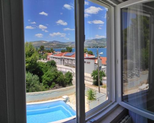 a window with a view of a swimming pool at Apartments Sollis in Trogir