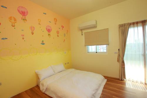 a bedroom with a white bed and balloons on the wall at Dali Moonlight B&B in Taitung City