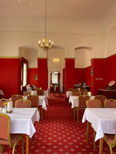 un comedor con paredes rojas, mesas y sillas blancas en WINDSOR SPA Hotel en Karlovy Vary