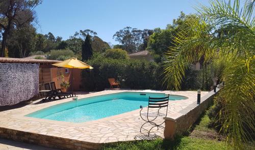 una piscina con una silla y una sombrilla en un patio en Chambre d'hôte Kalango proche de la plage-Piscine, en Lucciana