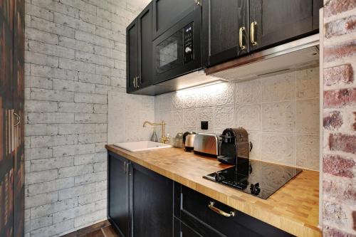 uma cozinha com armários pretos e um lavatório em Le studio du sorcier ! em Paris