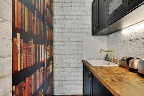 uma cozinha com um lavatório e uma parede de tijolos em Le studio du sorcier ! em Paris