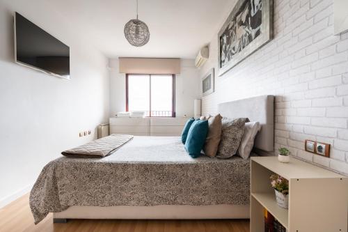 a white bedroom with a bed with blue pillows at Apartamento Levante en Chinchilla con vistas in Chinchilla de Monte Aragón