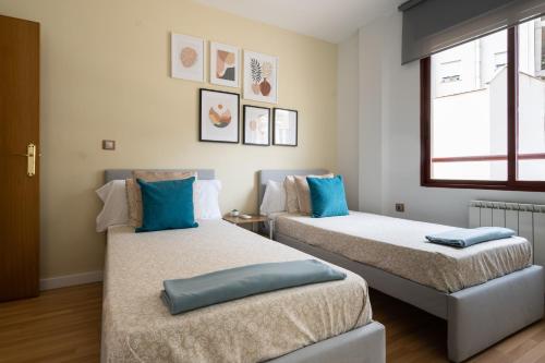 two beds in a room with blue pillows on them at Apartamento Levante en Chinchilla con vistas in Chinchilla de Monte Aragón
