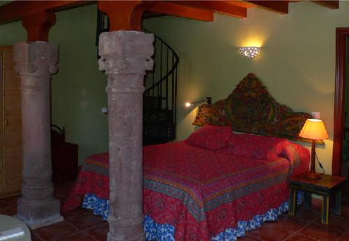 Cortijo Zalamea في Zalamea la Real: غرفة نوم بسرير لحاف احمر وعمودين