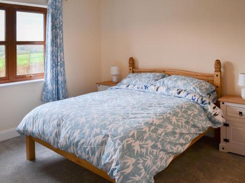 - une chambre avec un lit doté d'une couette bleue et d'une fenêtre dans l'établissement Quails Nest, à Edlingham