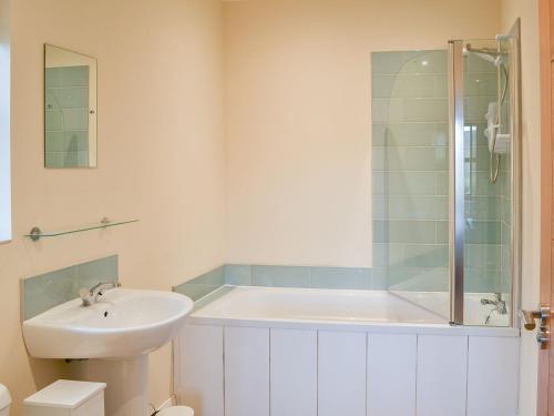 La salle de bains est pourvue d'une baignoire, d'un lavabo et d'une douche. dans l'établissement Quails Nest, à Edlingham