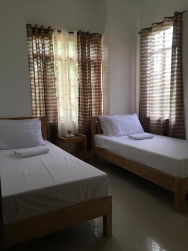 two beds in a room with two windows at capitol hills apartelle in Mamburao