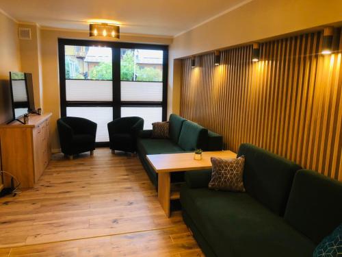 una sala de espera con sofás verdes y una mesa de madera. en Apartament Bajka, en Krynica-Zdrój