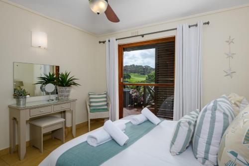 a bedroom with a bed and a desk and a window at San Lameer Villa 2536 - 3 Bedroom Superior - 6 pax - San Lameer Rental Agency in Southbroom