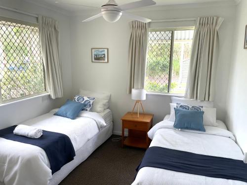 two beds in a room with two windows at 2 Bedroom Ground Level Villa in Tropical 4* Resort in Noosaville