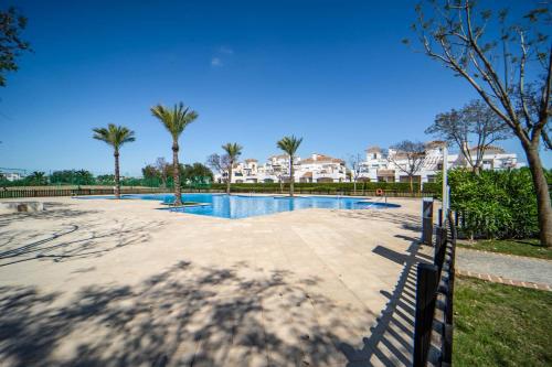 a swimming pool with palm trees and buildings in the background at PJA2-LT Bonita Villa localizado en La Torre Golf Resort in Torre-Pacheco