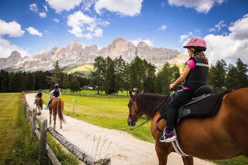a group of people riding horses down a dirt road at Angerle Alm Apt Rosengarten in Carezza al Lago