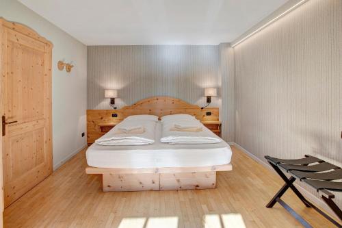 Schlafzimmer mit einem Bett mit einem Kopfteil aus Holz in der Unterkunft Chalet Sonne Superior2 4 in Livigno