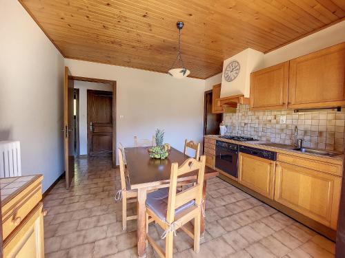 une cuisine avec des armoires en bois et une table et des chaises dans l'établissement APPARTEMENT-CENTRE-MORZINE-VUE PISTES-8-9 pers-BOIS VENANTS, à Morzine