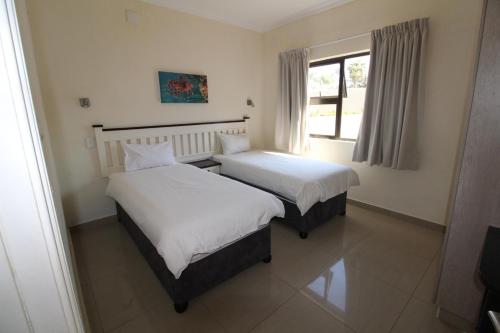 two beds in a room with a window at Saints View Resort Unit 6 in Uvongo Beach