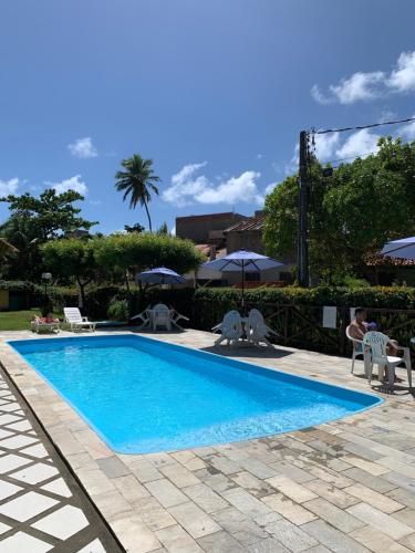 a blue swimming pool with chairs and umbrellas at Merepe Residence in Porto De Galinhas