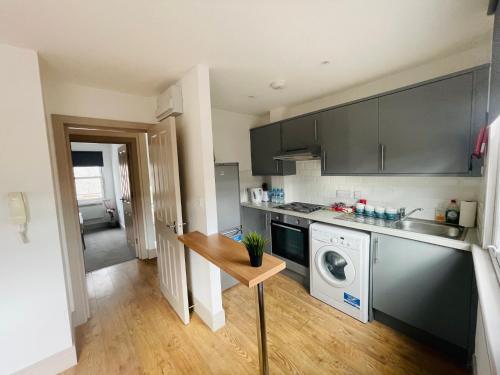 Lovely 1 bedroom apartment in London في لندن: مطبخ صغير مع غسالة ملابس وغسالة