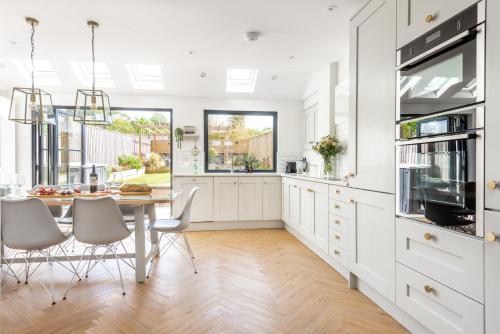 una cocina con armarios blancos y una mesa con sillas. en Holly Hayes House, en Instow