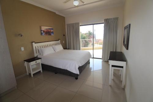 um quarto com uma cama e uma grande janela em Saints View Resort Unit 9 em Uvongo Beach