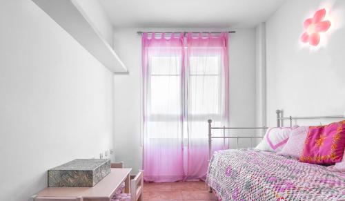 a bedroom with a bed and a window with pink curtains at Dúplex Playa in San José
