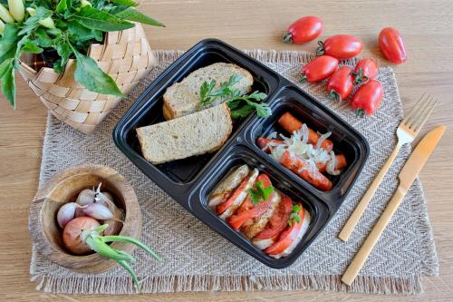 a lunch box with a tray of food with tomatoes and bread at Osada Bachledzki Wierch Odkryj Zakopane in Zakopane