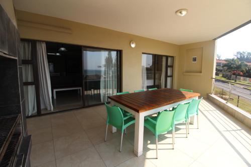 a dining room with a table and green chairs at Saints View Resort Unit 12 in Uvongo Beach