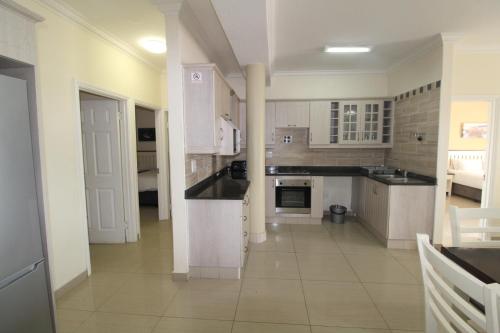 a kitchen with white cabinets and black counter tops at Saints View Resort Unit 12 in Uvongo Beach