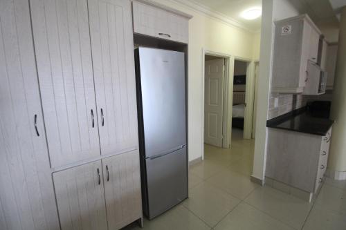 a kitchen with white cabinets and a refrigerator at Saints View Resort Unit 12 in Uvongo Beach