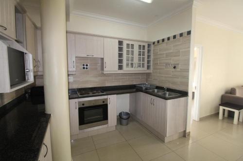 a kitchen with white cabinets and a stove top oven at Saints View Resort Unit 12 in Uvongo Beach