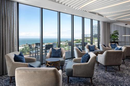 a waiting room with chairs and tables and windows at Premier Hotel Umhlanga in Durban