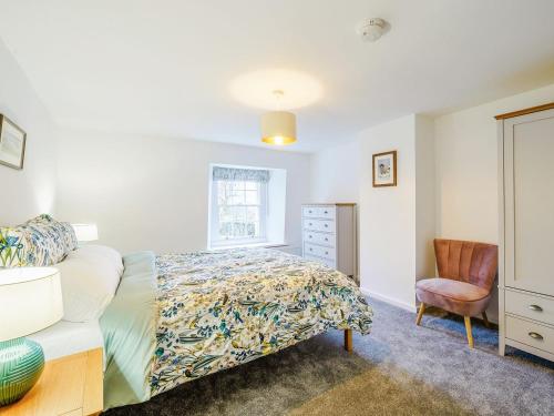 a bedroom with a bed and a chair at Branthwaite Cottage in Caldbeck