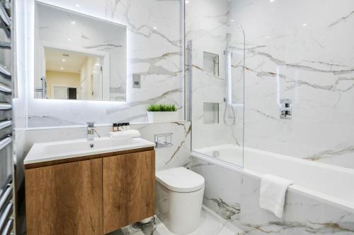 La salle de bains est pourvue d'un lavabo, de toilettes et d'une baignoire. dans l'établissement Roomspace Serviced Apartments - Lockwood House, à Surbiton
