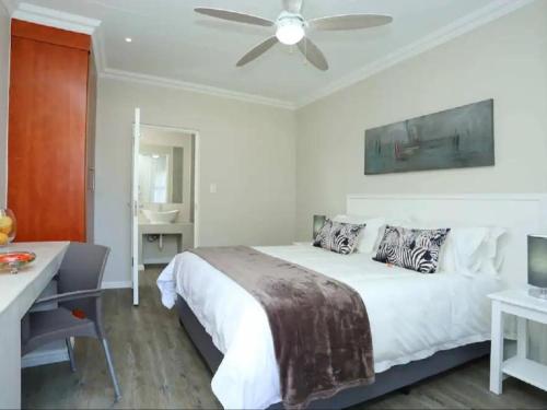 a white bedroom with a bed and a ceiling fan at Eagle Cove in Honeydew