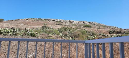 a fence with a hill in the background at Lovely 3-bedroom apartment in Marsalforn, Gozo! in Marsalforn