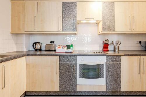 a kitchen with wooden cabinets and a white oven at Roomspace Serviced Apartments- Regents Court in Kingston upon Thames