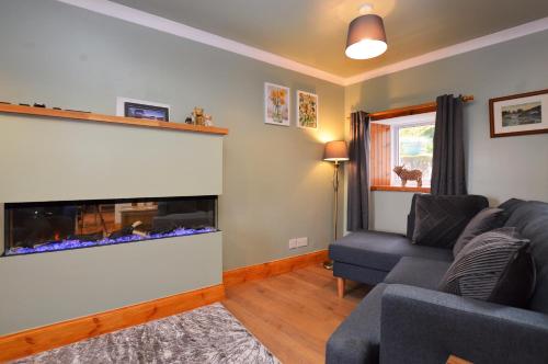 a living room with a couch and a fish tank at Chapelton Cottage in Strachur