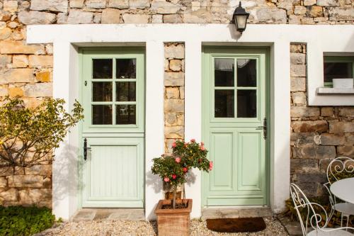 two green doors on a stone building with a table and chairs at Gîtes Isatis in Arbonne-la-Foret