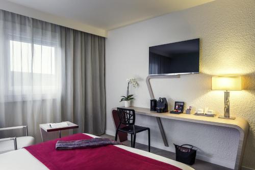 a hotel room with a bed and a desk at Mercure Paris Le Bourget Aeroport in Le Blanc-Mesnil